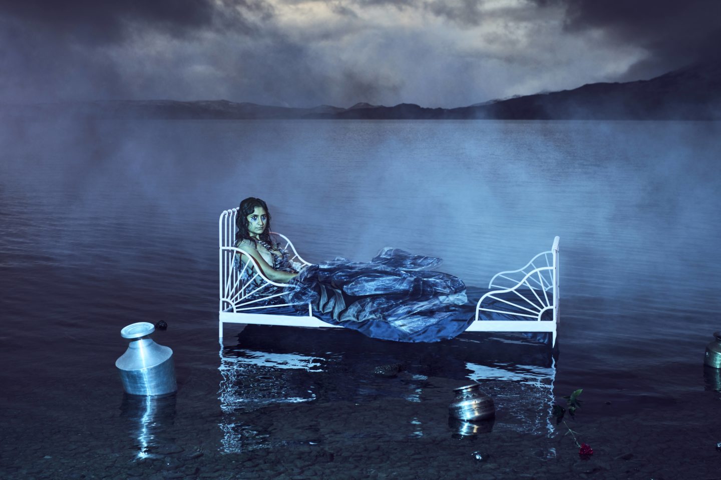 A woman lies in a bed which stands in water