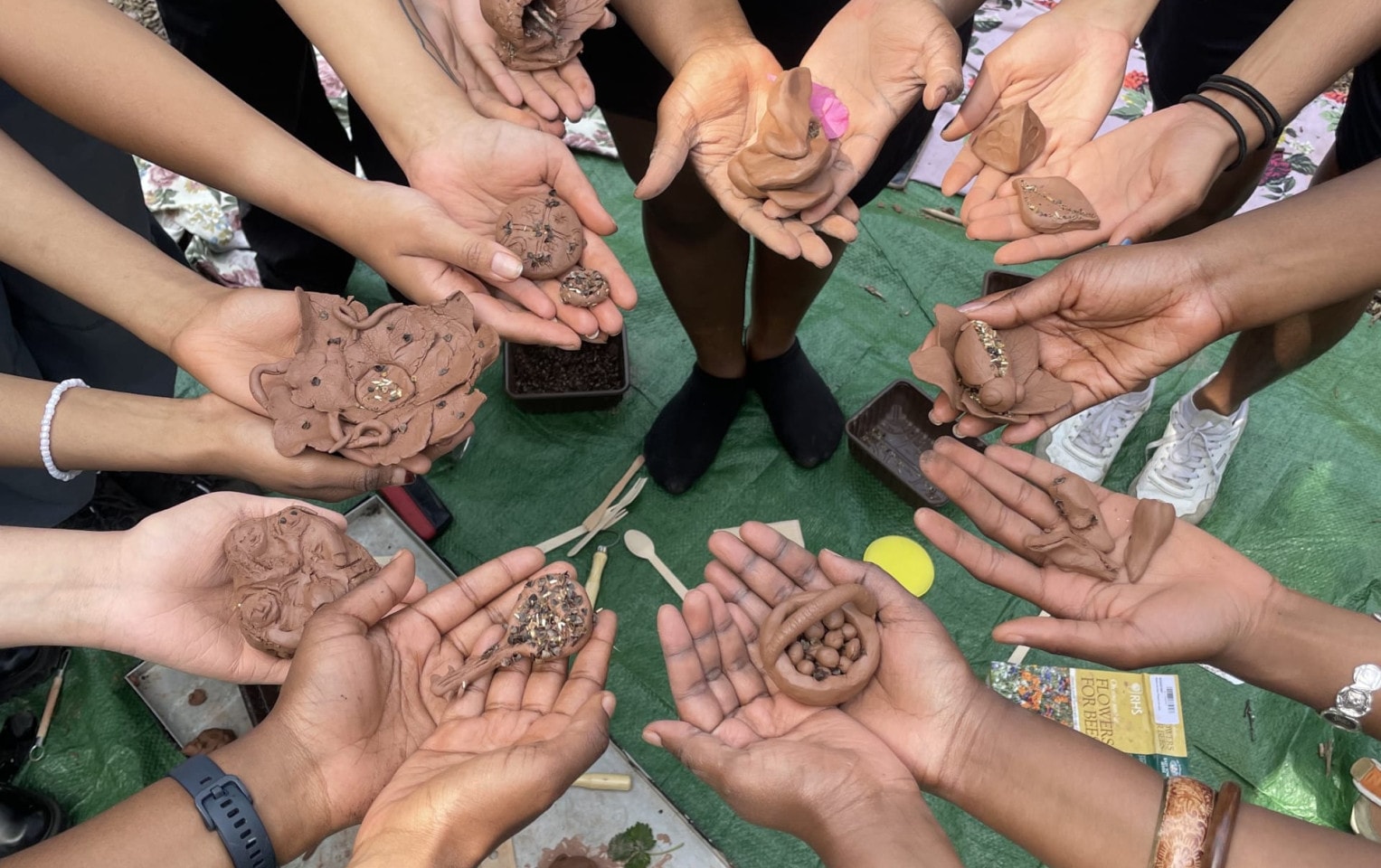 A circle of hands presenting clay sculptures